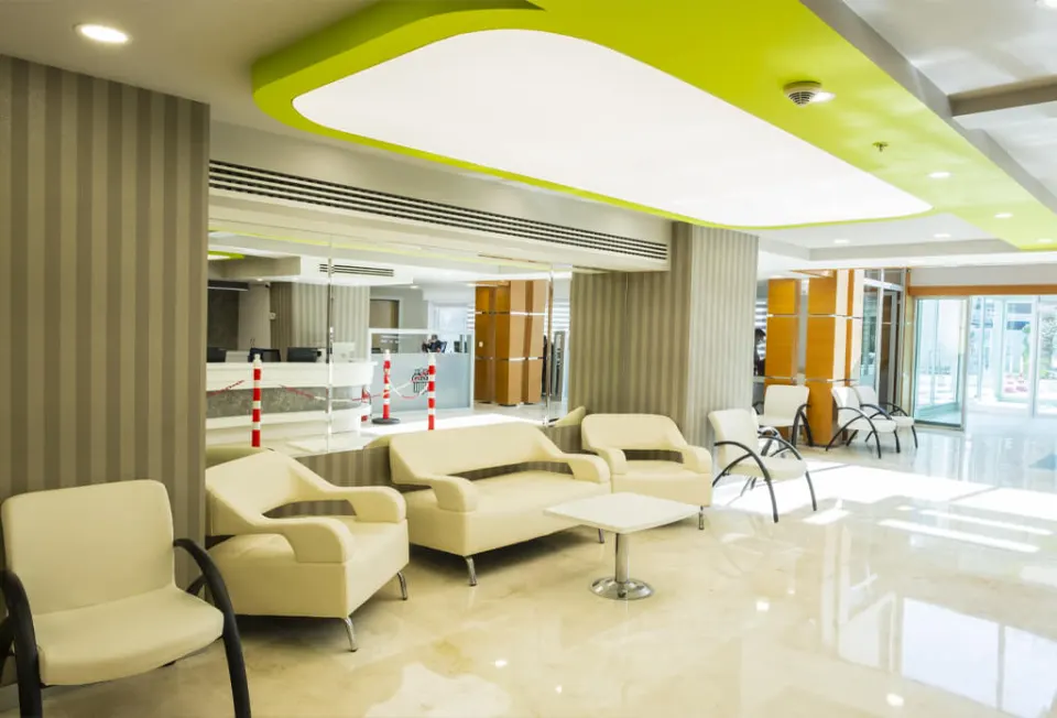 The reception and seating area of the hospital in Antalya, with pale armchairs and a marble floor.
